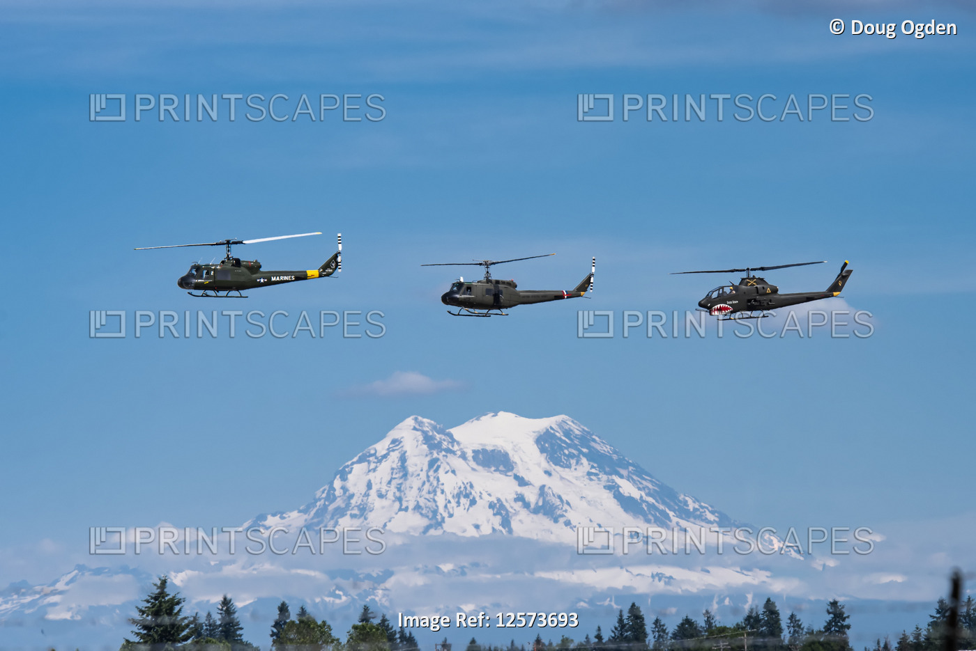 A pair of UH-1 Huey Helicopters and an AH-1 Cobra fly in formation with Mount ...