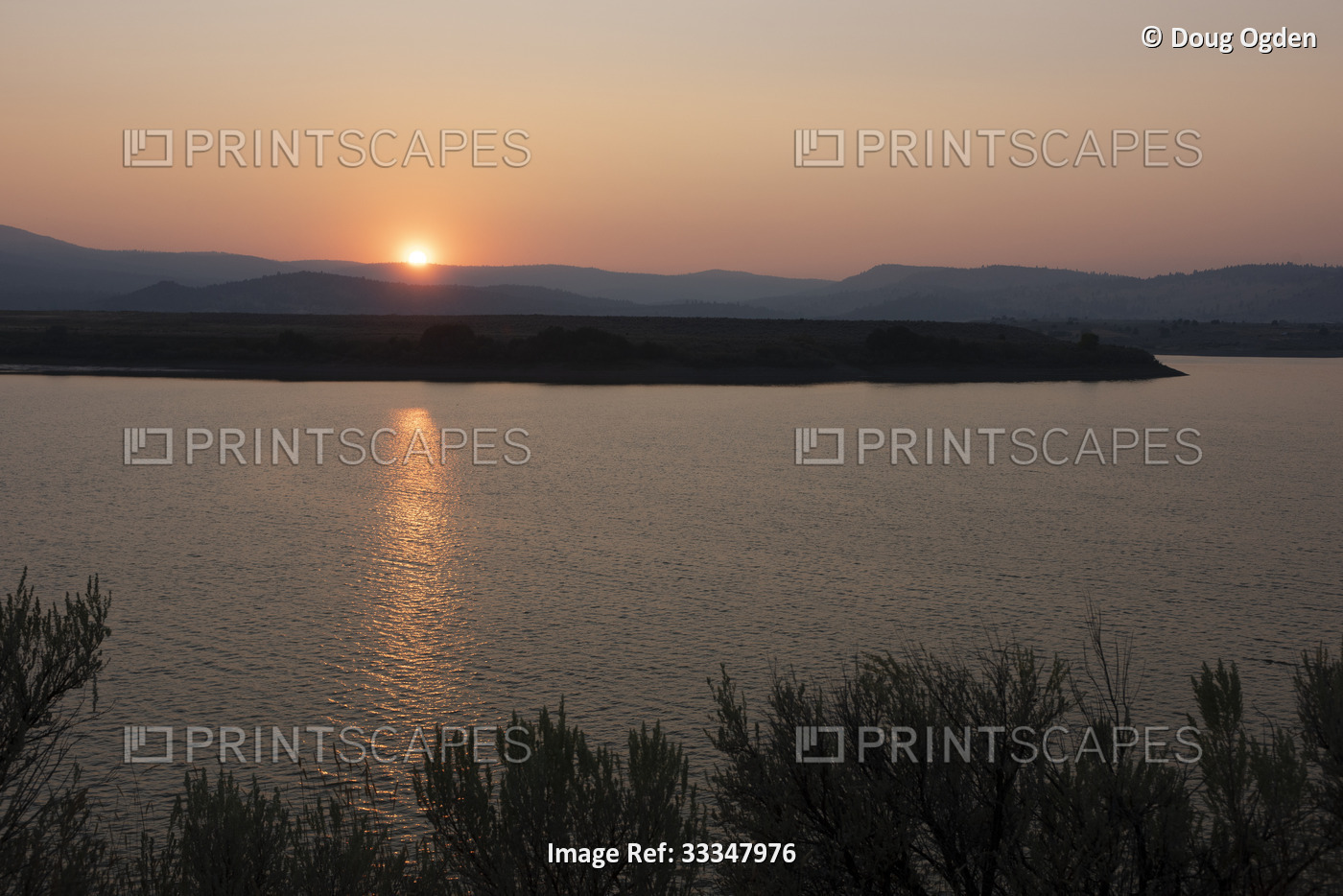 Smoky sky mutes the beautiful sunset reflecting over Unity Reservoir at the ...